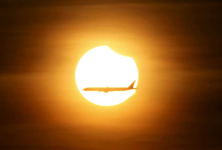 Zatmění slunce a prolétávající letadlo nad Singapurem
