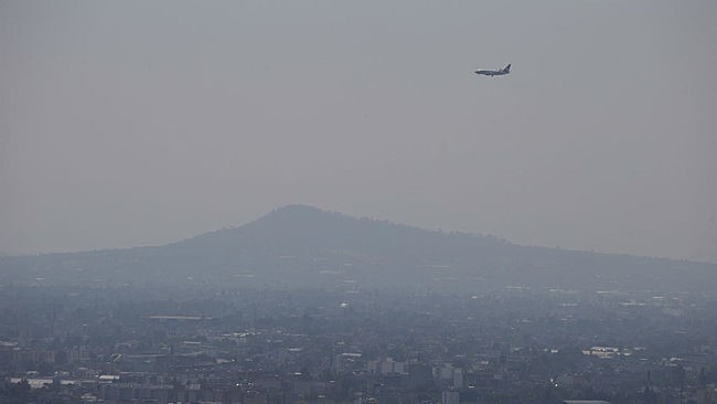 Letící letadlo nad městem plném smogu